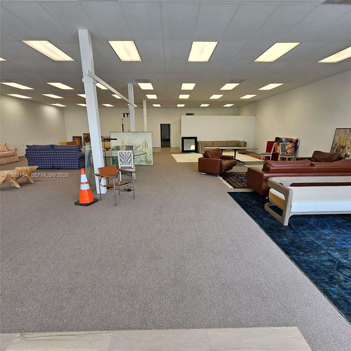 A large, open-plan showroom features gray carpeting, white walls, and various pieces of furniture — 2025 13th Ave, FL 32960, FL