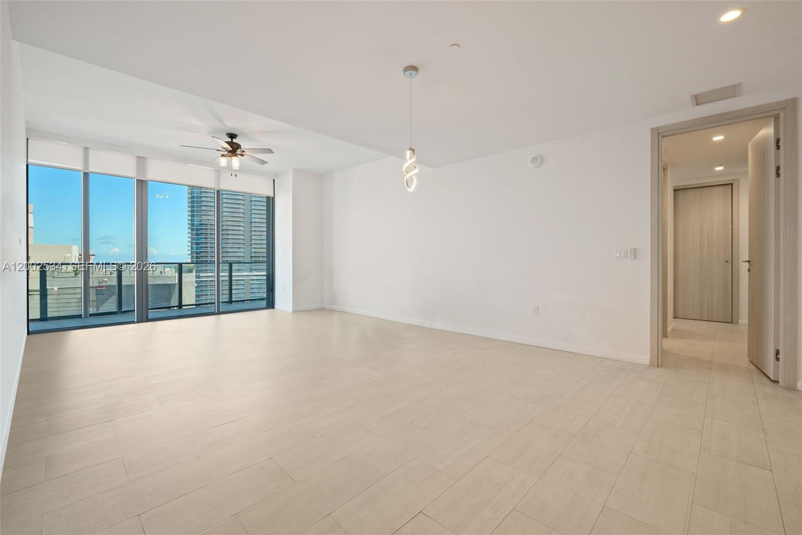 An empty room features light-colored tile flooring, a modern pendant light, and floor-to-ceiling windows — 1000 Brickell Plz, Miami FL 33131, MIAMI, FL