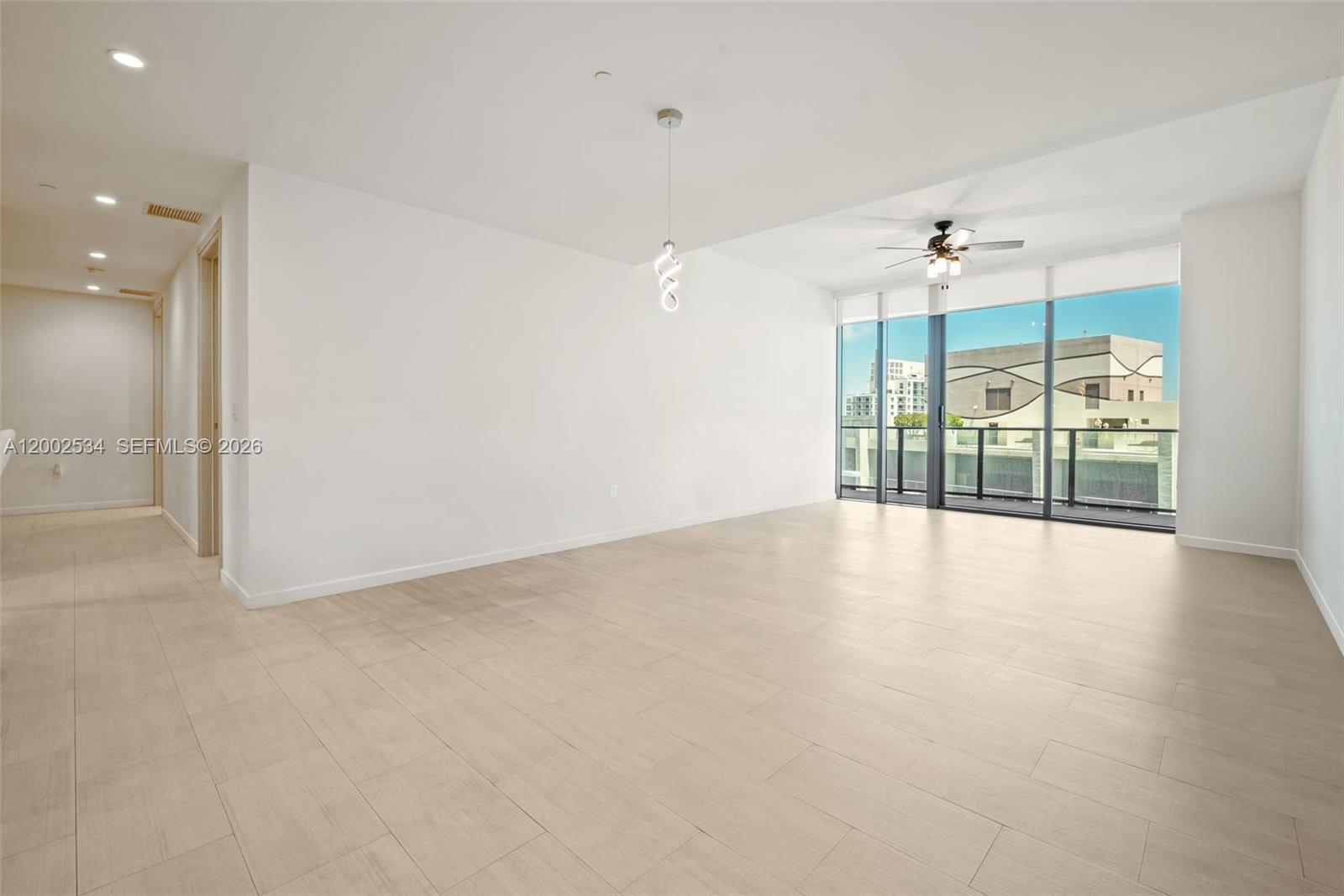 An empty living room features light-colored tile flooring, a ceiling fan, and floor-to-ceiling windows — 1000 Brickell Plz, Miami FL 33131, MIAMI, FL