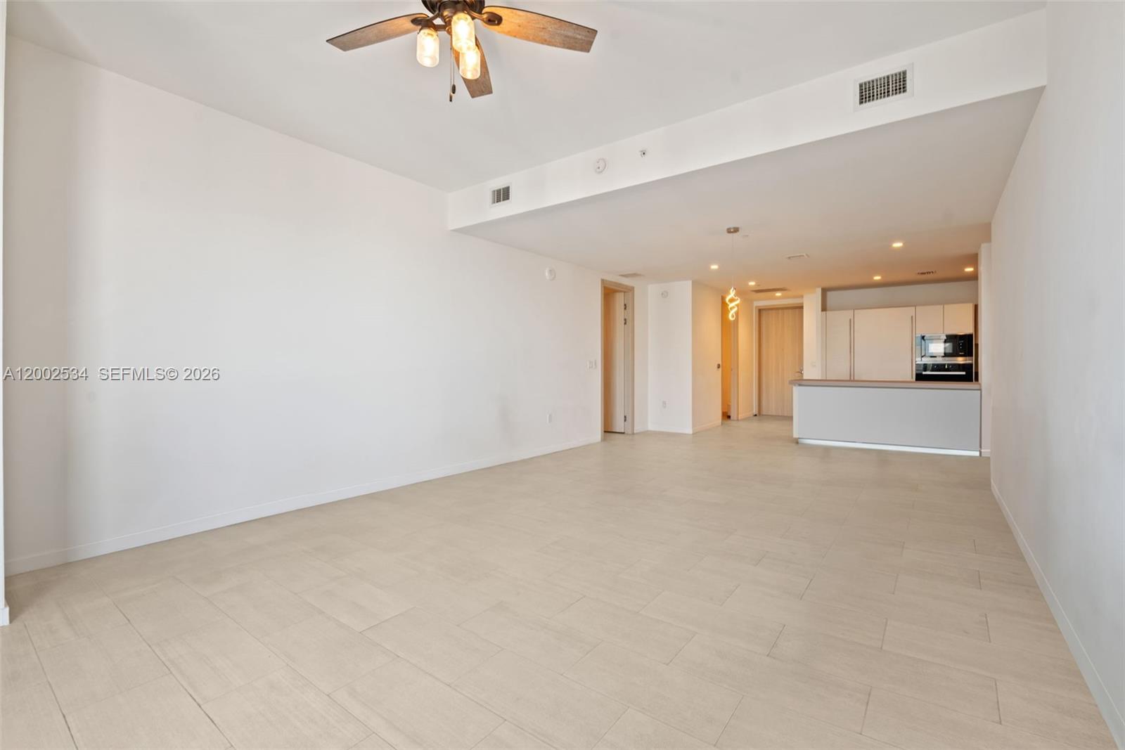 An open-concept living area features light tile flooring, a ceiling fan, and a kitchen — 1000 Brickell Plz, Miami FL 33131, MIAMI, FL