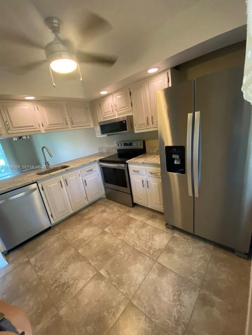 A kitchen features white cabinets, stainless steel appliances, granite countertops, and tiled flooring — 2703 Nassau Bnd # E2, Coconut Creek FL 33066, COCONUT CREEK, FL
