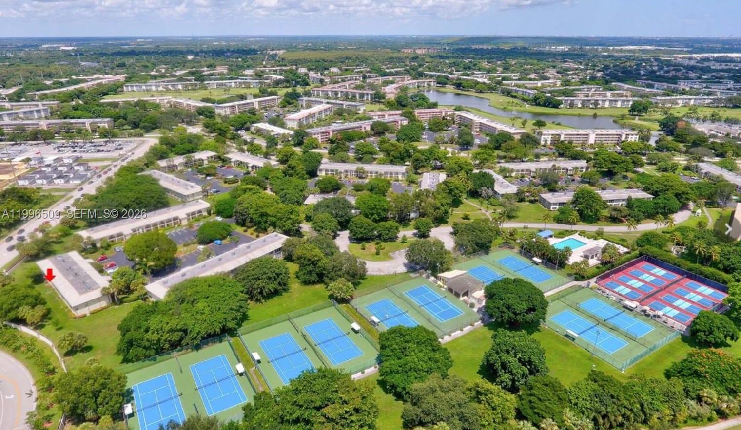 An aerial view of a residential complex featuring multiple tennis courts and a swimming pool — 2703 Nassau Bnd # E2, Coconut Creek FL 33066, COCONUT CREEK, FL