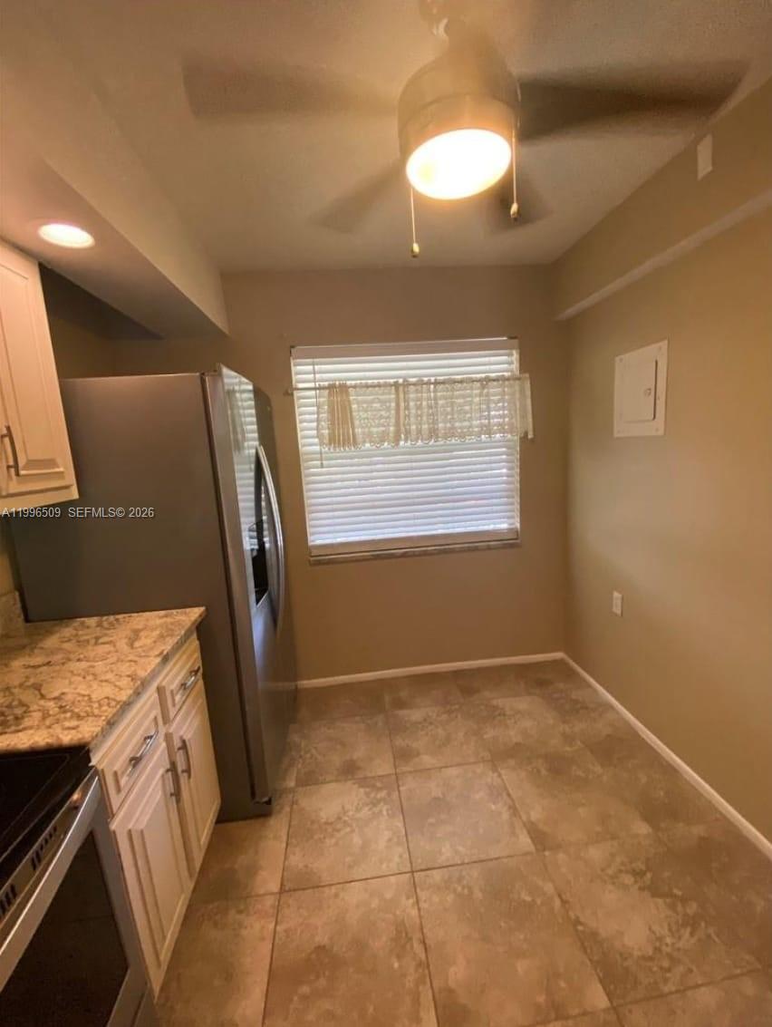A kitchen features tile flooring, white cabinets, granite countertops, and a stainless steel refrigerator — 2703 Nassau Bnd # E2, Coconut Creek FL 33066, COCONUT CREEK, FL