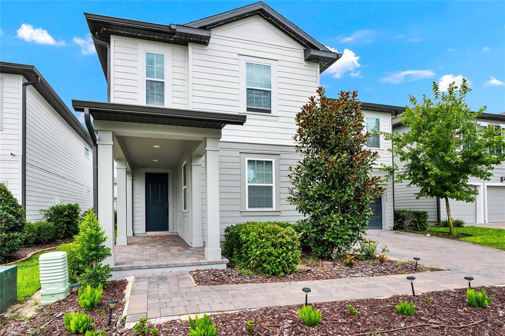 A two-story house features white and gray horizontal siding, a covered porch, and paved walkways — 17018 SEVILLE ORANGE ROAD, WINTER GARDEN, FL