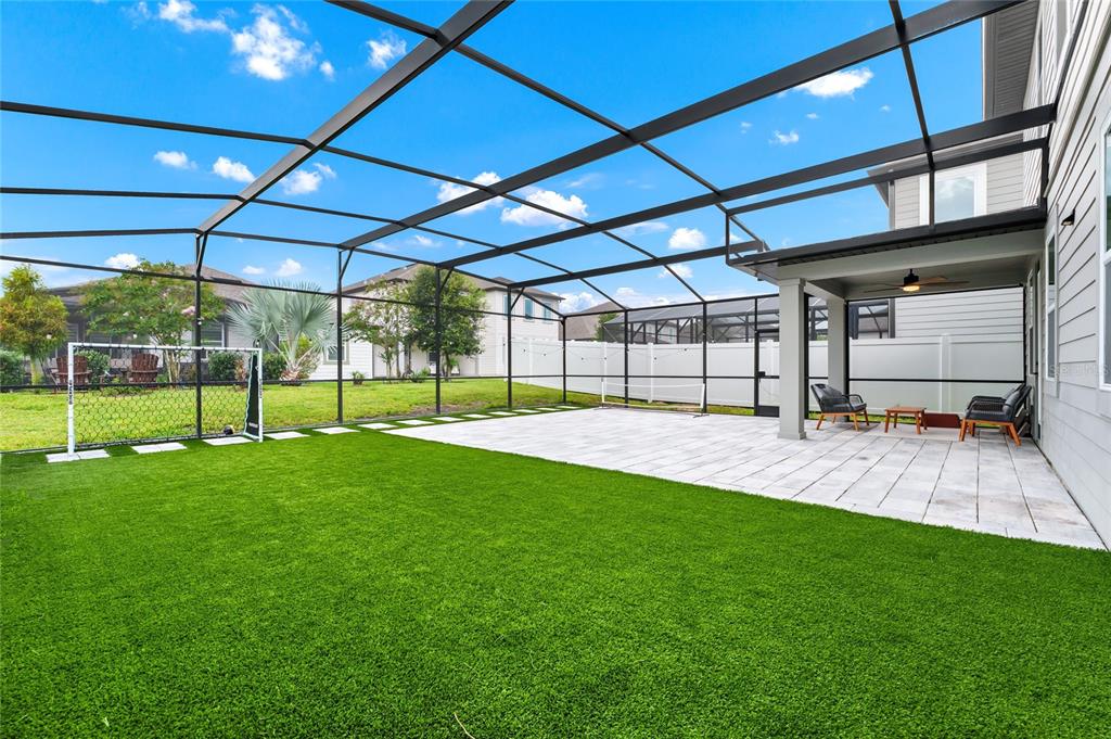 A screened-in patio features artificial turf, a soccer goal, and a paved seating area — 17018 SEVILLE ORANGE ROAD, WINTER GARDEN, FL