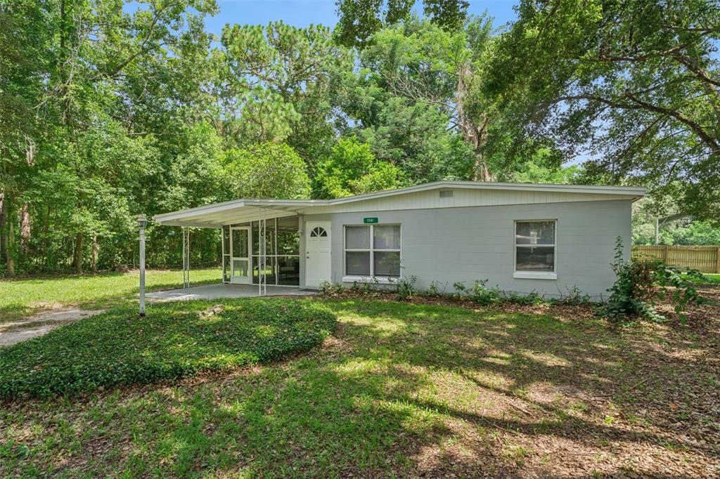 A single-story gray house with a screened-in porch sits on a wooded lot — 2581 JANS WAY, ALTAMONTE SPRINGS, FL