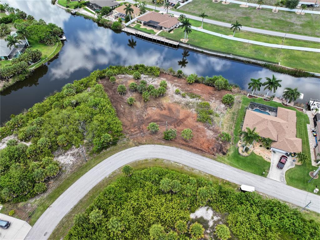 An aerial view shows a vacant waterfront lot situated between two houses and a road — 14235 FRUITPORT CIRCLE, PORT CHARLOTTE, FL