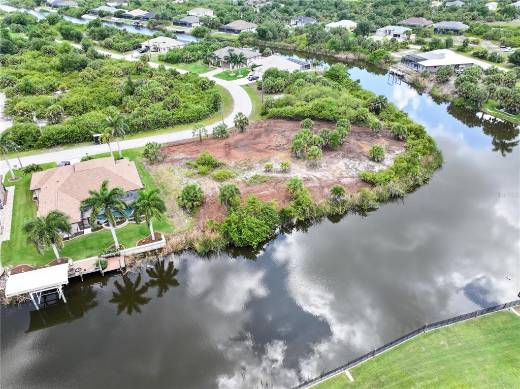 An aerial view shows a vacant waterfront lot next to a house with a dock — 14235 FRUITPORT CIRCLE, PORT CHARLOTTE, FL