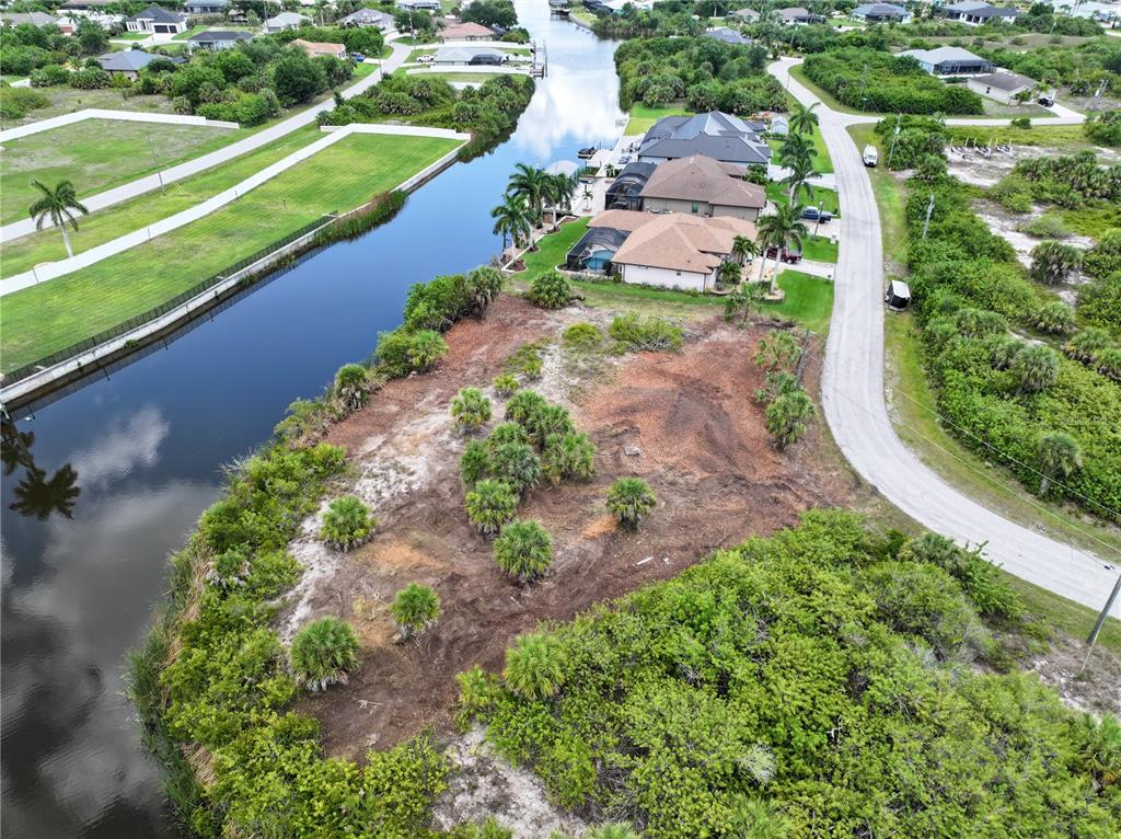 An aerial view shows a vacant, partially cleared waterfront lot next to a residential street — 14235 FRUITPORT CIRCLE, PORT CHARLOTTE, FL