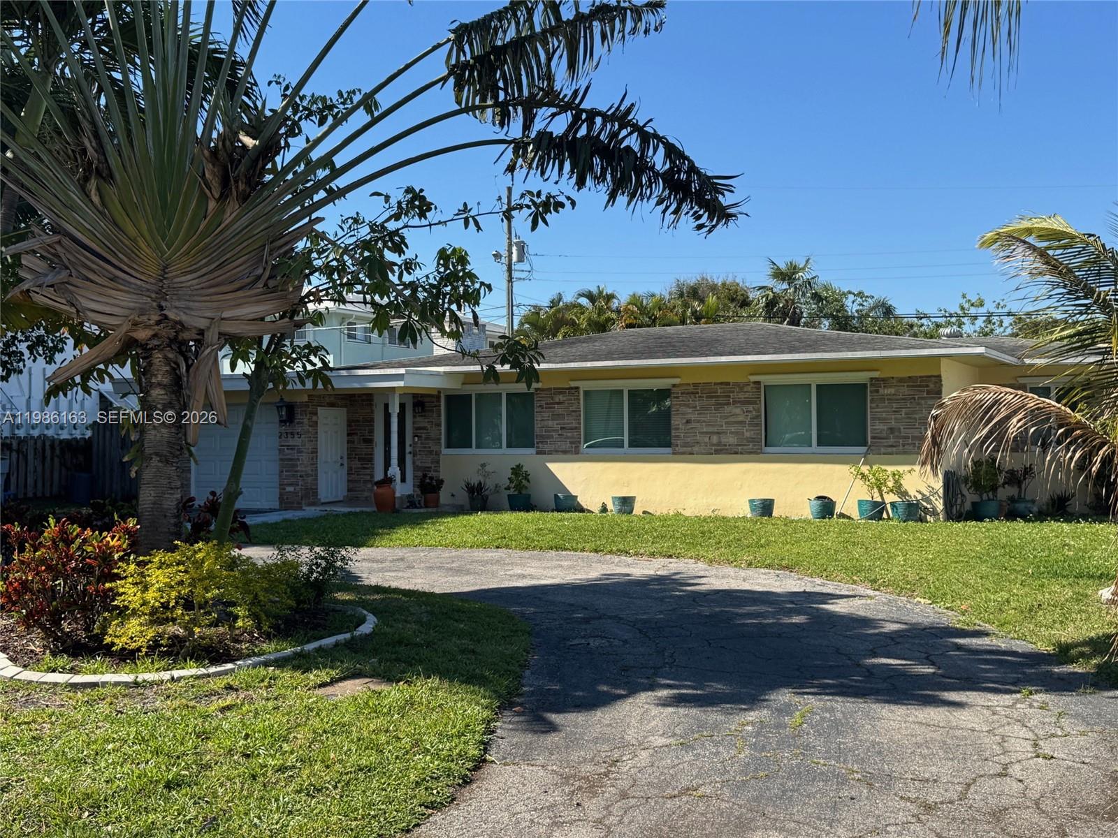 A single-story house with a yellow facade, stone accents, and a curved driveway — 2355 SE 7th St, Pompano Beach FL 33062, POMPANO BEACH, FL