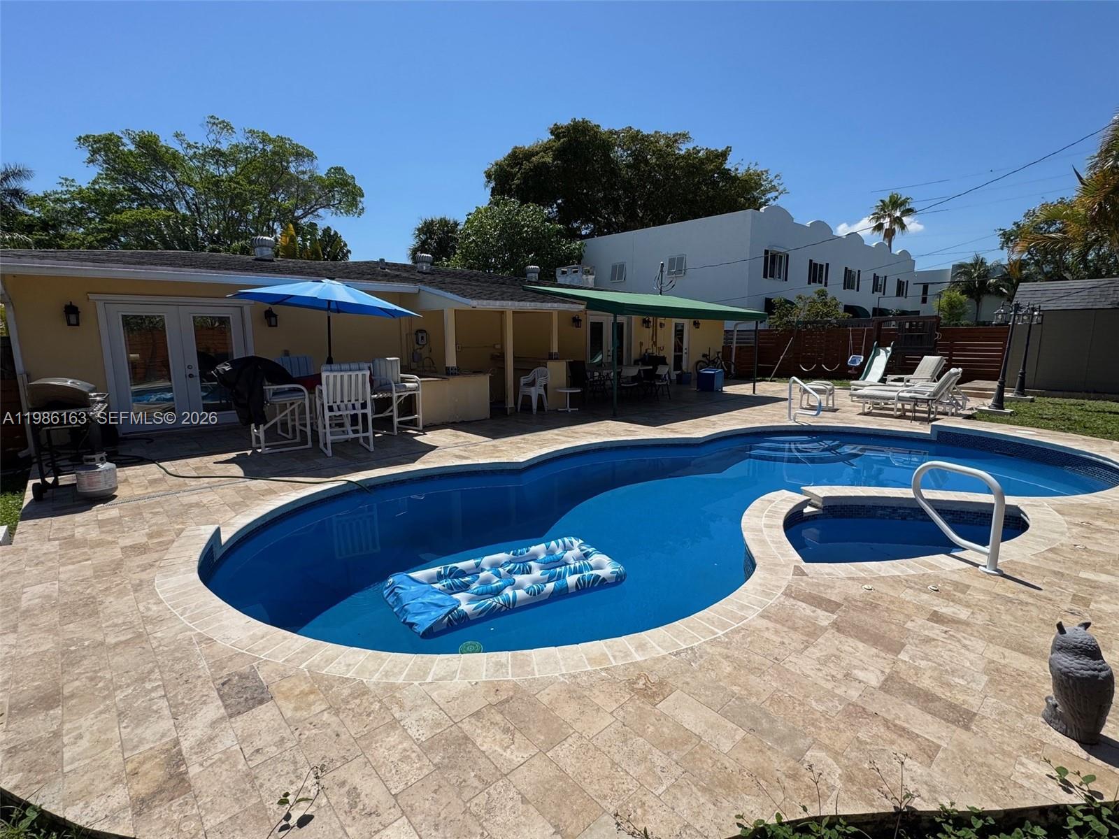 A backyard features a swimming pool with a spa, patio furniture, and a covered porch — 2355 SE 7th St, Pompano Beach FL 33062, POMPANO BEACH, FL