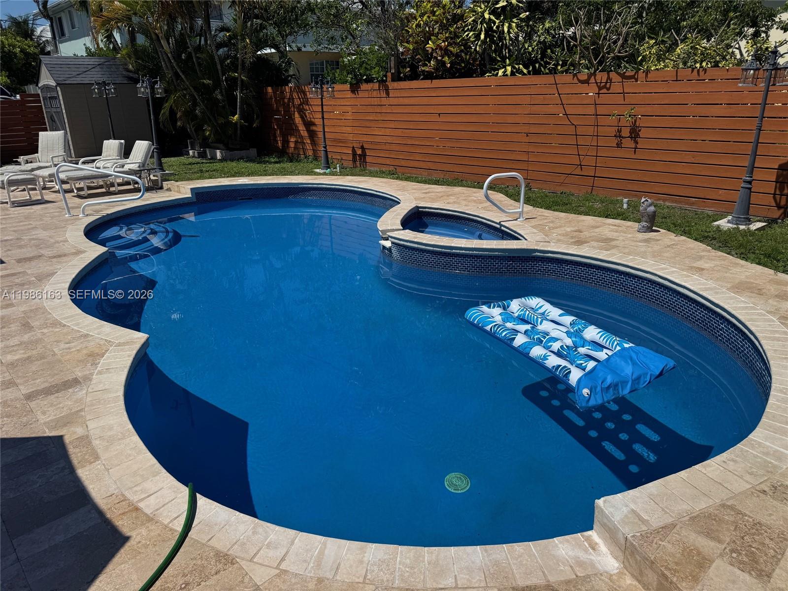 A backyard swimming pool with a spa, patio furniture, and a wooden privacy fence — 2355 SE 7th St, Pompano Beach FL 33062, POMPANO BEACH, FL
