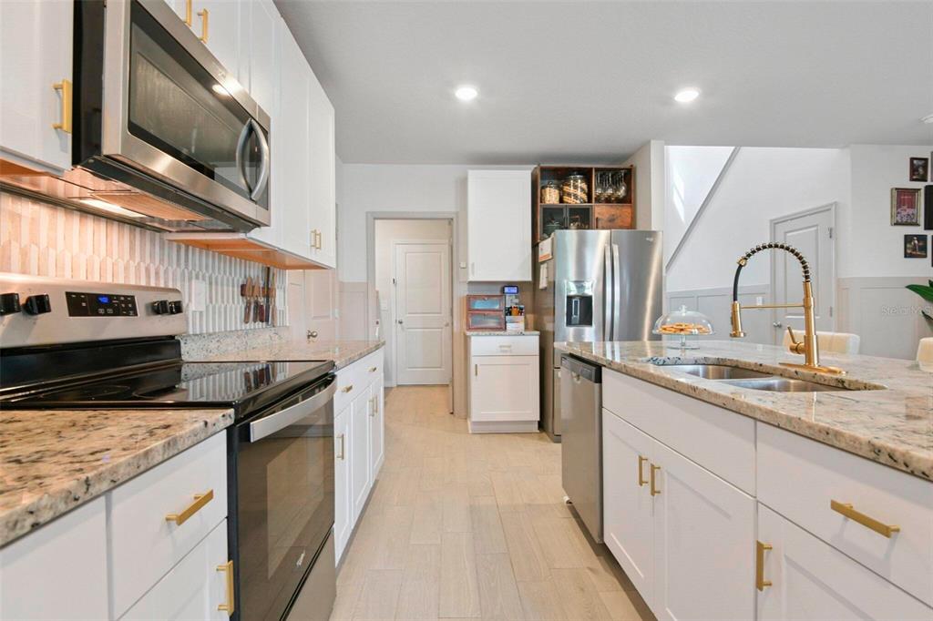 A modern kitchen features white cabinets, stainless steel appliances, and a granite-topped island — 3610 RADIANT MOUNTAIN DRIVE, PLANT CITY, FL
