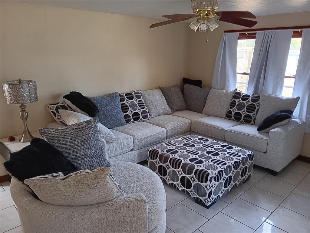 A living room features a large sectional sofa, a patterned ottoman, and a ceiling fan — 5647 19TH STREET, ZEPHYRHILLS, FL