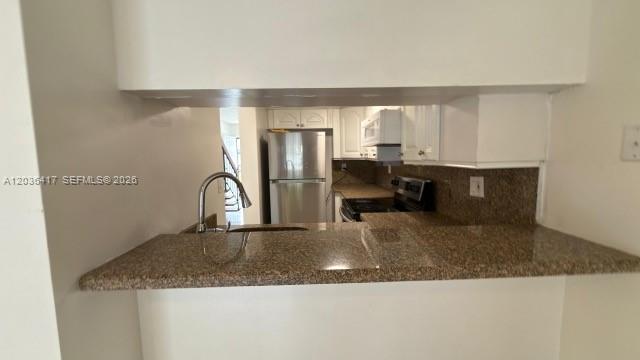 A kitchen features a granite breakfast bar, stainless steel refrigerator, and white cabinetry — 5388 W 24th Ave # 110, Hialeah FL 33016, HIALEAH, FL