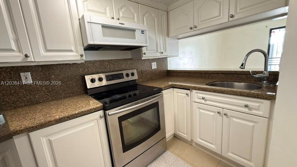 A kitchen features white cabinets, granite countertops, and stainless steel appliances — 5388 W 24th Ave # 110, Hialeah FL 33016, HIALEAH, FL