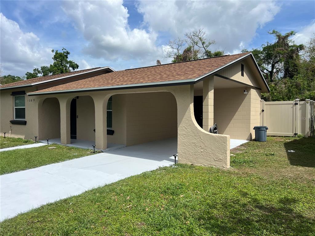 A single-story house features a tan stucco exterior, a brown shingled roof, and a carport — 1069 PRINCEWOOD, ORLANDO, FL