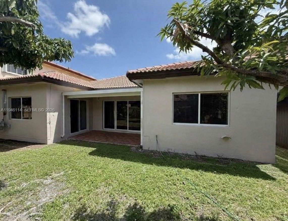 The exterior view shows a beige house with a covered patio and a grassy backyard — 22844 SW 114th Ave, Miami FL 33170, MIAMI, FL