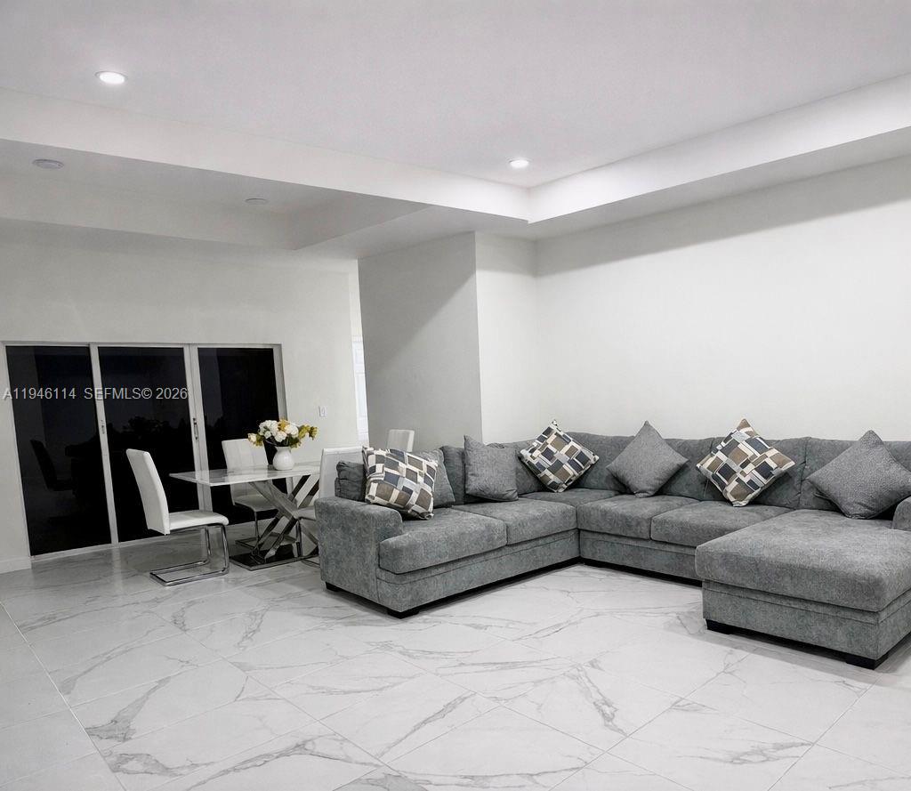A living room features a large gray sectional sofa, white tile flooring, and a dining area — 22844 SW 114th Ave, Miami FL 33170, MIAMI, FL