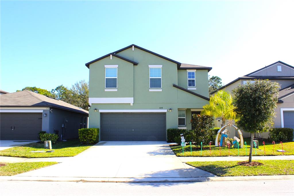 A two-story, light green suburban house with a two-car garage and a concrete driveway — 2058 STELLAR BRILLIANCE WAY, LUTZ, FL