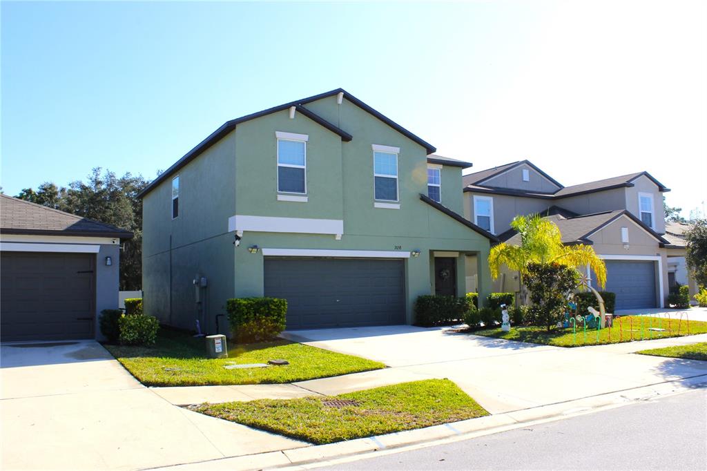 A two-story green house with a two-car garage and a concrete driveway — 2058 STELLAR BRILLIANCE WAY, LUTZ, FL