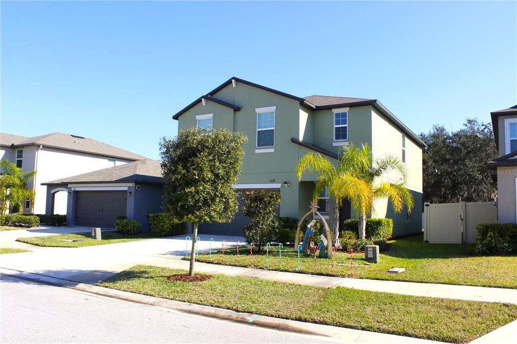 A two-story, light green house with a garage and a front yard — 2058 STELLAR BRILLIANCE WAY, LUTZ, FL