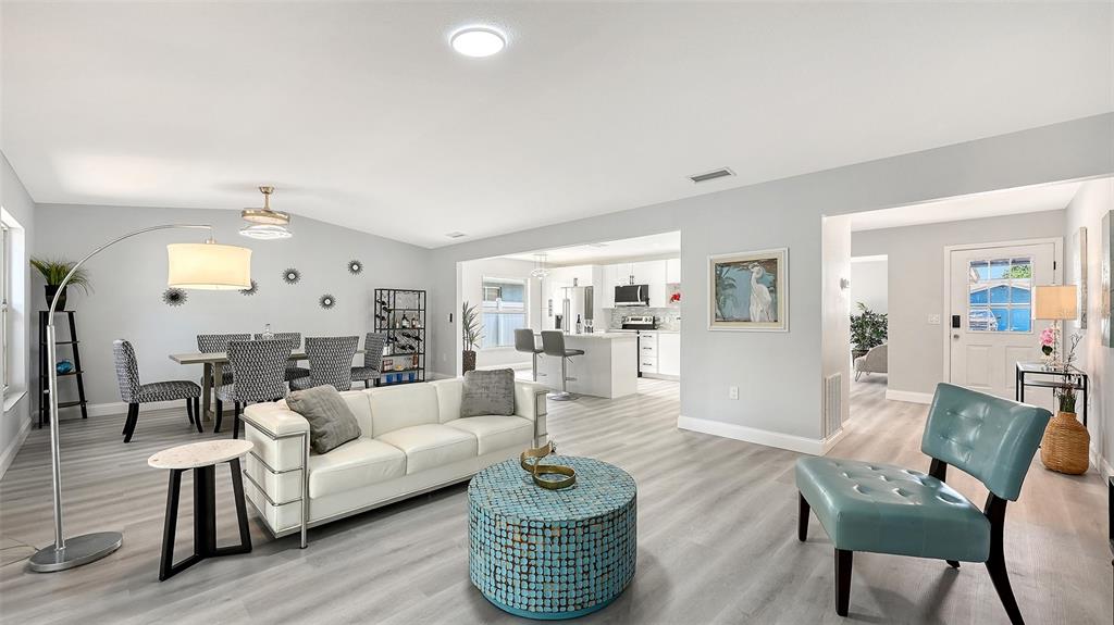 An open-concept living and dining area features light gray flooring, white walls, and modern furniture — 4054 PALAU DRIVE, SARASOTA, FL