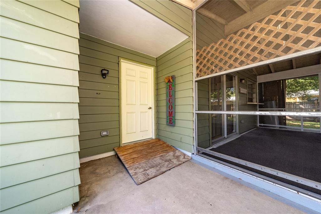 A wooden ramp leads to a white front door on a covered porch with siding — 14644 SW 35TH TERRACE ROAD, OCALA, FL