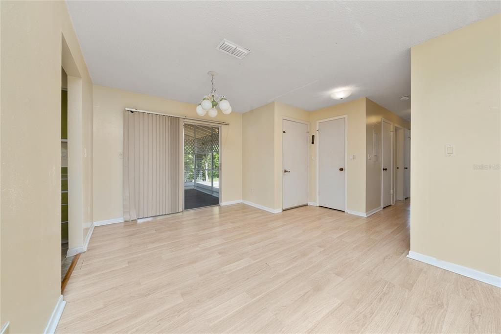An empty dining room with light wood-look flooring, a chandelier, and sliding glass patio doors — 14644 SW 35TH TERRACE ROAD, OCALA, FL