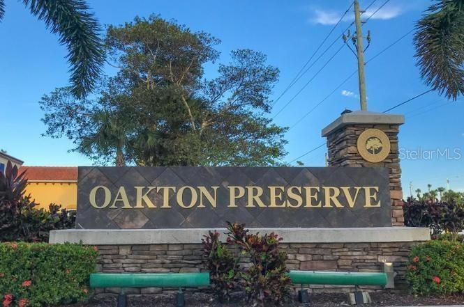 A stone monument sign for Oakton Preserve stands outdoors with landscaping and a utility pole — 2086 FOXTAIL VIEW COURT, WEST PALM BEACH, FL