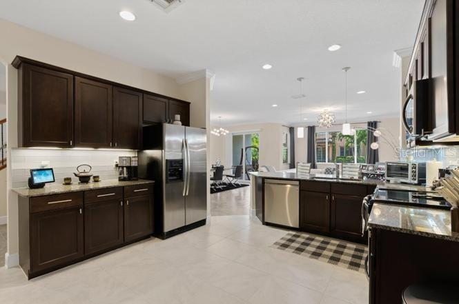 A kitchen features dark wood cabinets, stainless steel appliances, and light tile flooring — 2086 FOXTAIL VIEW COURT, WEST PALM BEACH, FL