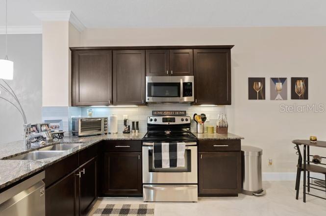 A kitchen features dark wood cabinets, stainless steel appliances, and granite countertops — 2086 FOXTAIL VIEW COURT, WEST PALM BEACH, FL