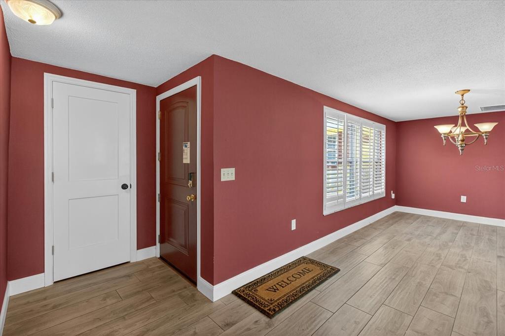 An entryway with red walls, wood-look tile flooring, and a white door — 12805 FIFTH ISLE, HUDSON, FL