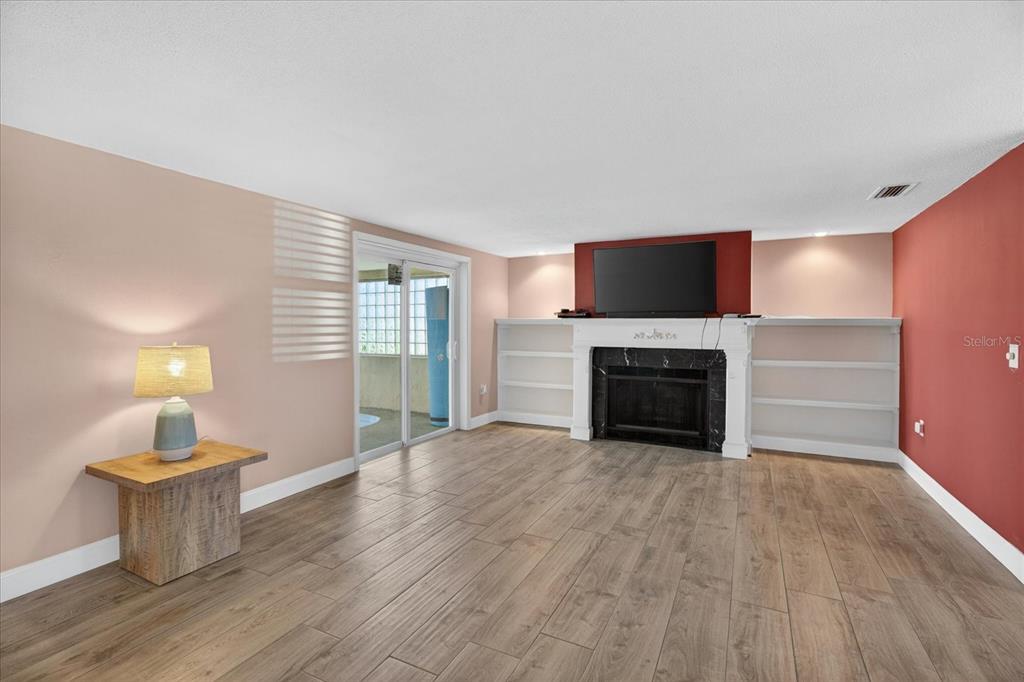 A living room features wood-look tile flooring, a fireplace with built-in shelving, and sliding doors — 12805 FIFTH ISLE, HUDSON, FL