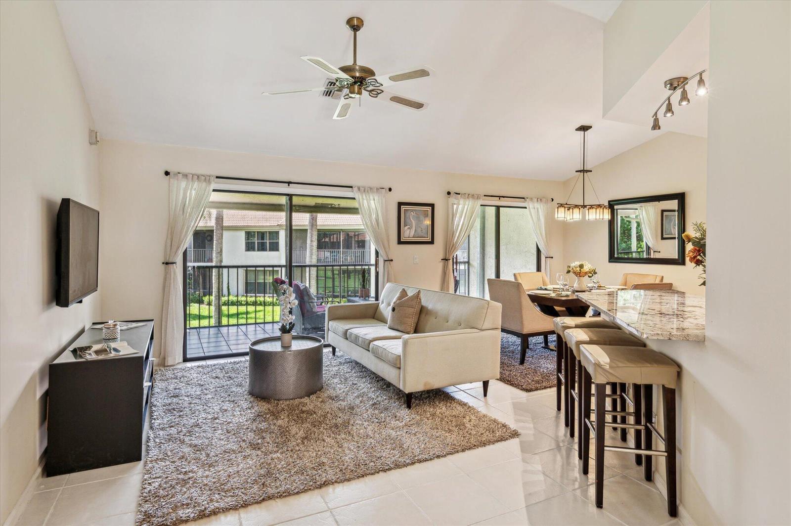 A living and dining area with a sofa, breakfast bar, and sliding glass balcony doors — 5750 Coach House Circle # G, Boca Raton FL 33486, BOCA RATON, FL