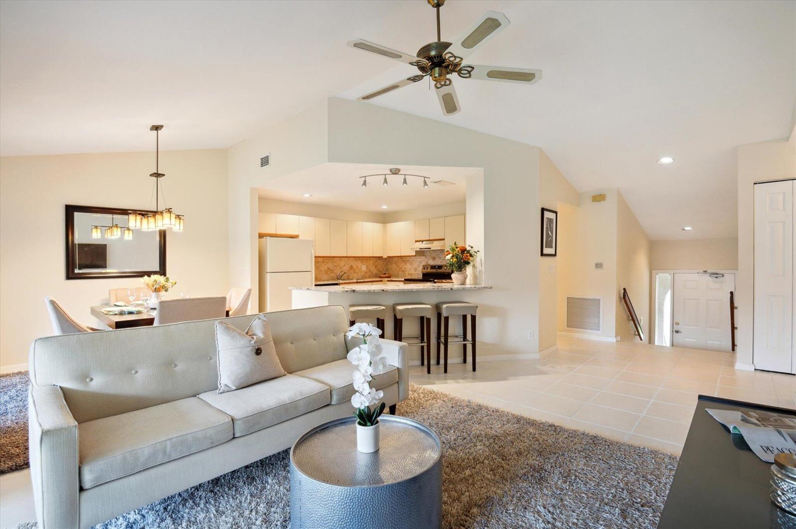 A living room with a sofa, coffee table, and ceiling fan opens to a kitchen — 5750 Coach House Circle # G, Boca Raton FL 33486, BOCA RATON, FL