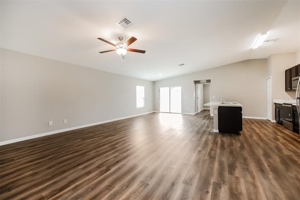 An open-concept living area features wood-look flooring, a ceiling fan, and a kitchen island — 3637 STARBOARD AVENUE, NORTH PORT, FL