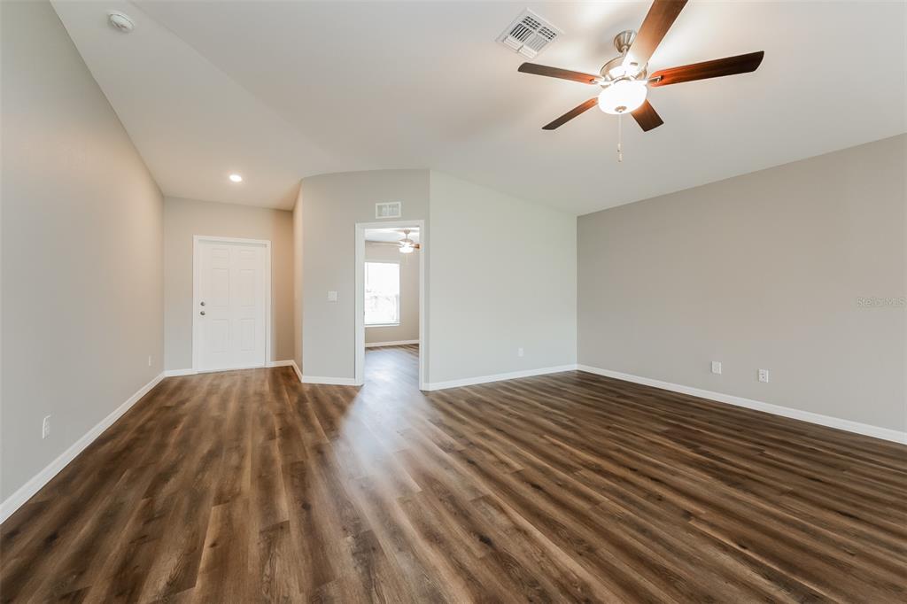 An empty room with wood-look flooring, a ceiling fan, and a doorway leading to another room — 3637 STARBOARD AVENUE, NORTH PORT, FL