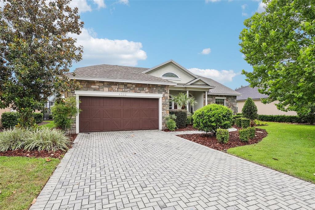 A single-story house with a stone facade, brown garage door, and a paved driveway — 4322 TOKOSE PLACE, LAKELAND, FL