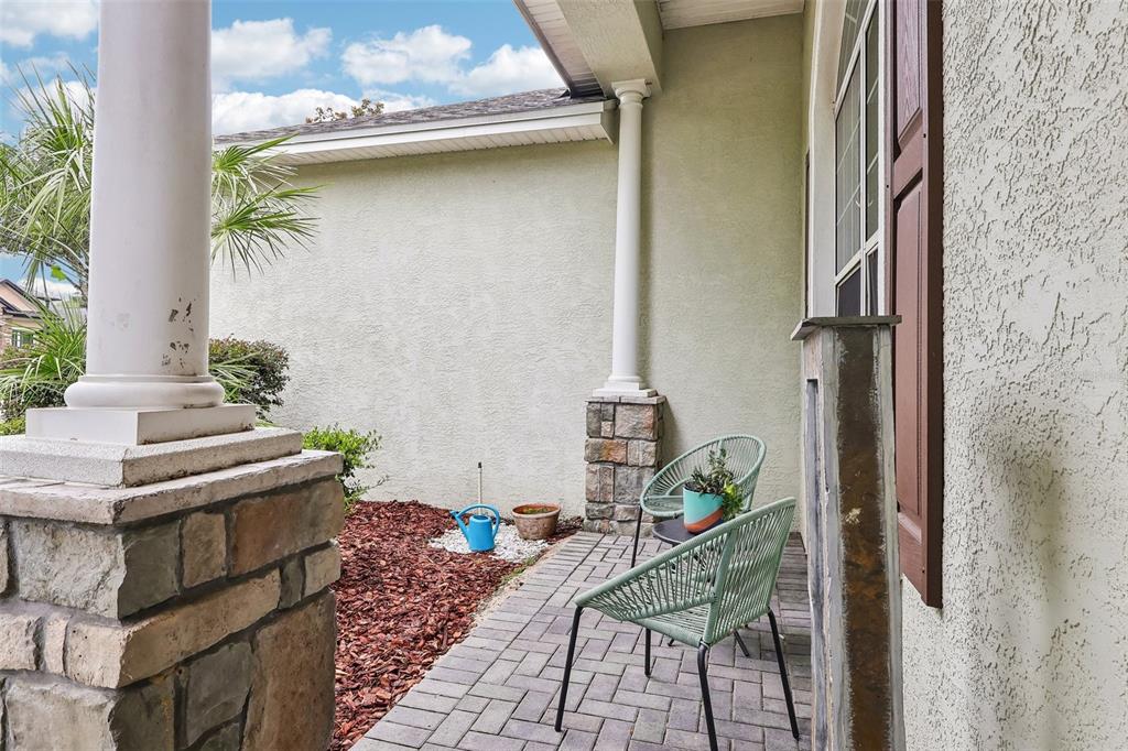 A paved patio area features two green chairs, a small table, and a stone pillar — 4322 TOKOSE PLACE, LAKELAND, FL