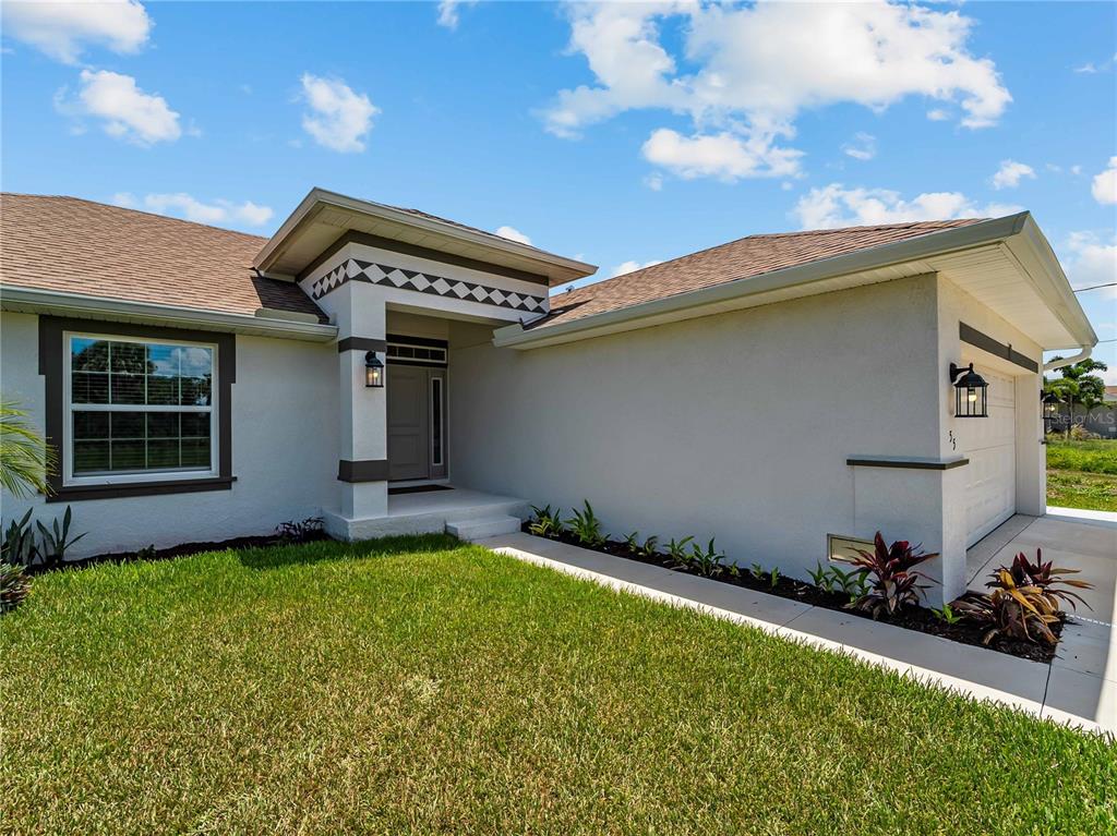 The exterior of a single-story house features a covered entryway, stucco walls, and a garage — 55 PINE VALLEY LANE, ROTONDA WEST, FL