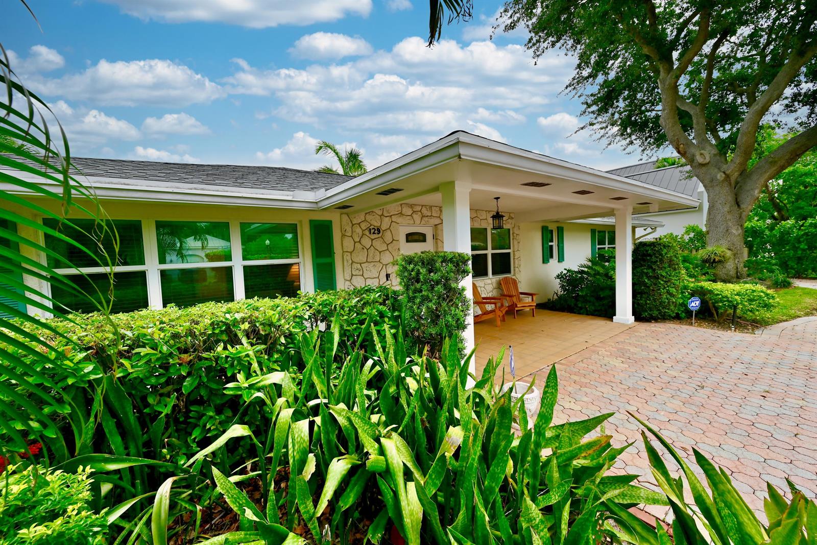 A single-story house exterior features a stone-faced entryway, a covered porch, and a paved driveway — 129 Alhambra Place, West Palm Beach FL 33405, WEST PALM BEACH, FL