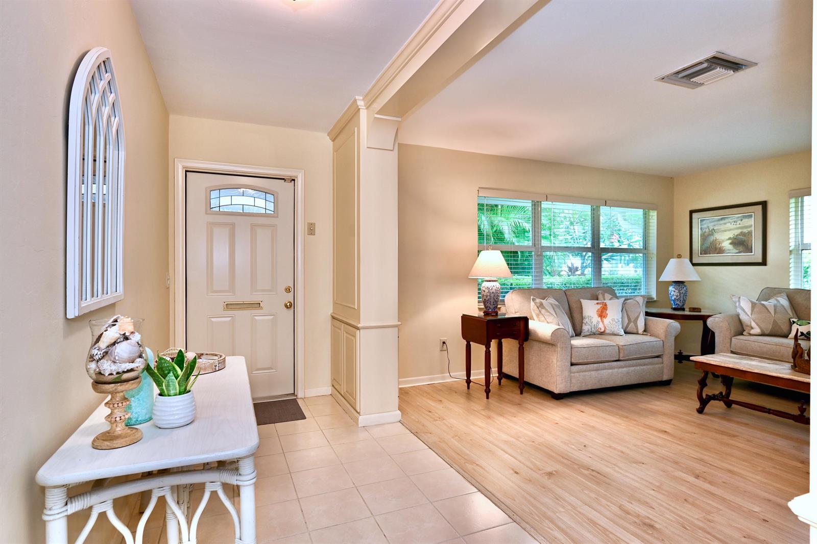 An entryway with tile flooring leads into a living room featuring light wood-look flooring — 129 Alhambra Place, West Palm Beach FL 33405, WEST PALM BEACH, FL