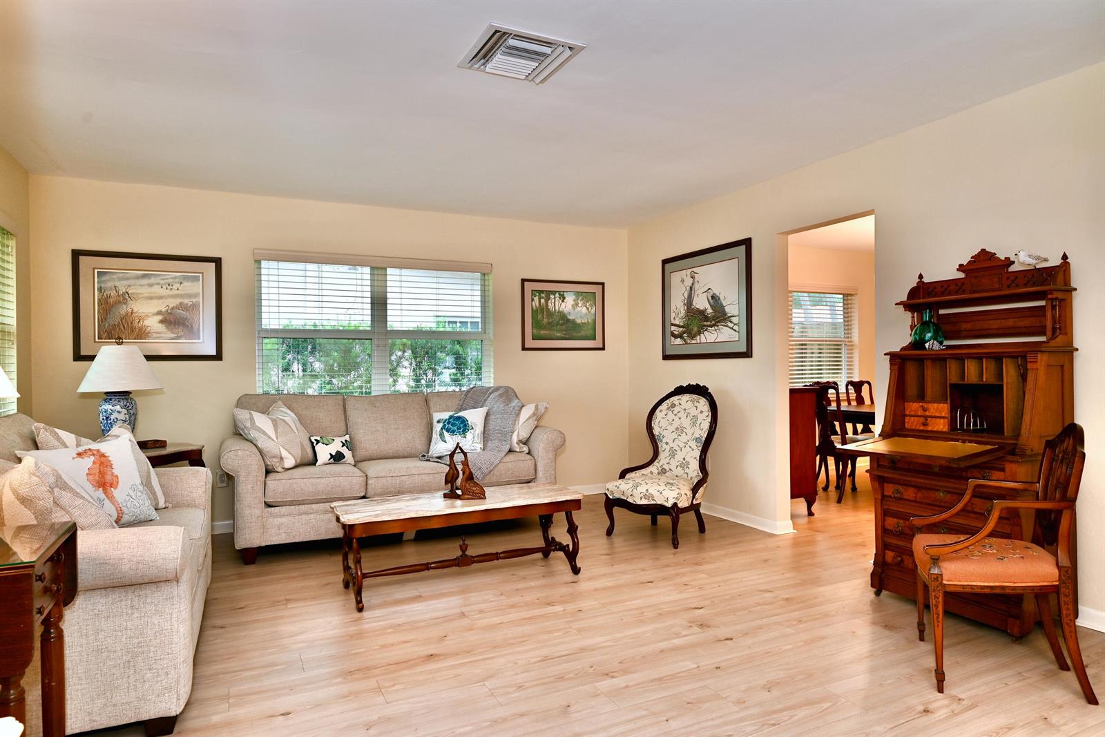 A living room features light wood-look flooring, a beige sofa, and a wooden secretary desk — 129 Alhambra Place, West Palm Beach FL 33405, WEST PALM BEACH, FL