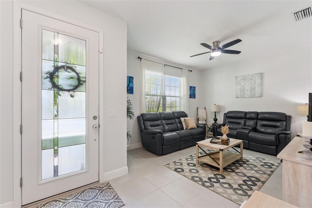 A living room features two dark leather sofas, a patterned area rug, and a front door — 1144 CAVENDER CREEK ROAD, MINNEOLA, FL