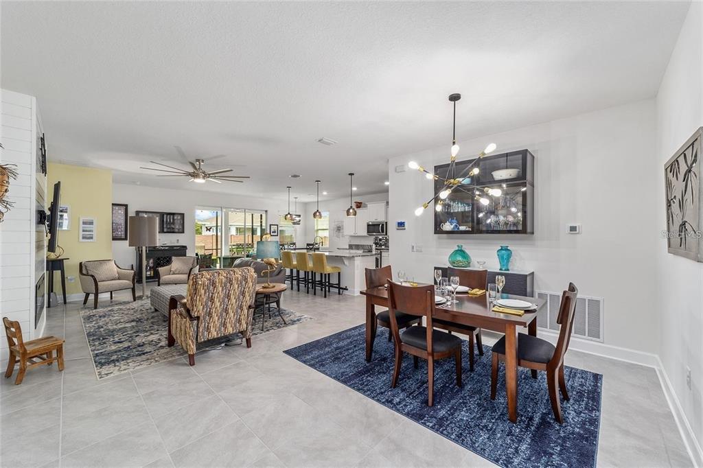 An open-concept living and dining area features tile flooring, a modern chandelier, and kitchen seating — 4395 NW 55TH TERRACE, OCALA, FL