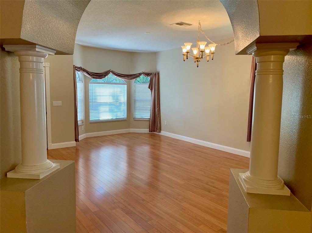 A dining room with hardwood floors, a bay window, and two decorative columns — 13024 ROYAL GEORGE AVENUE, ODESSA, FL