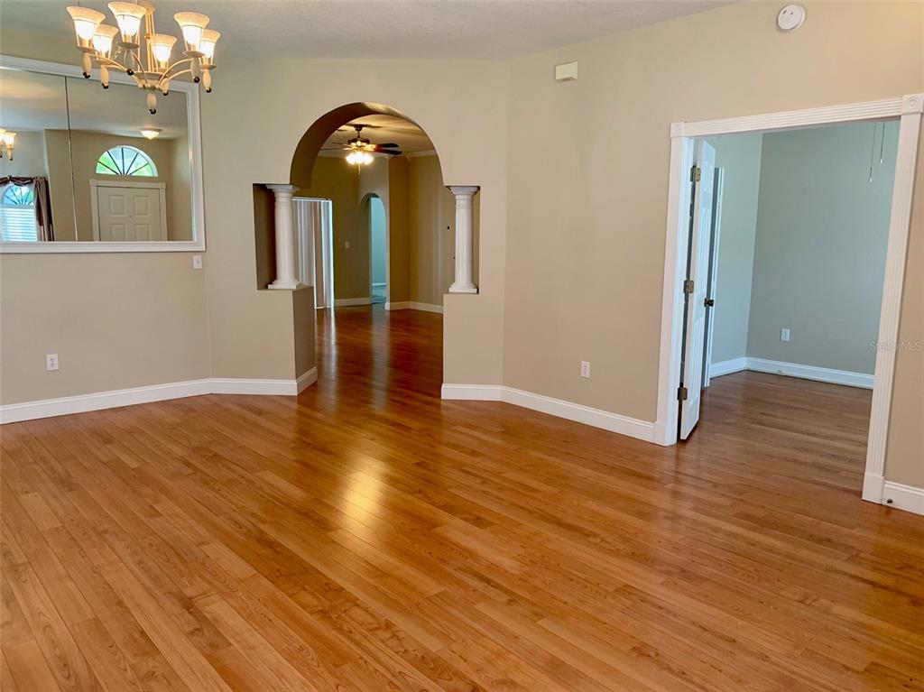 A room with hardwood floors, an arched entryway, and a chandelier reflected in a mirror — 13024 ROYAL GEORGE AVENUE, ODESSA, FL