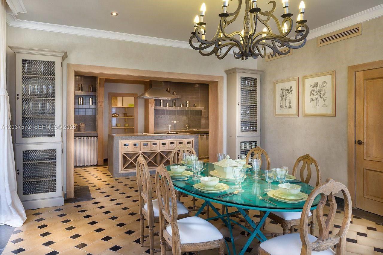 A dining room with a glass table, chandelier, and adjacent kitchen with tiled flooring — 0 Cana cap, FL, FL