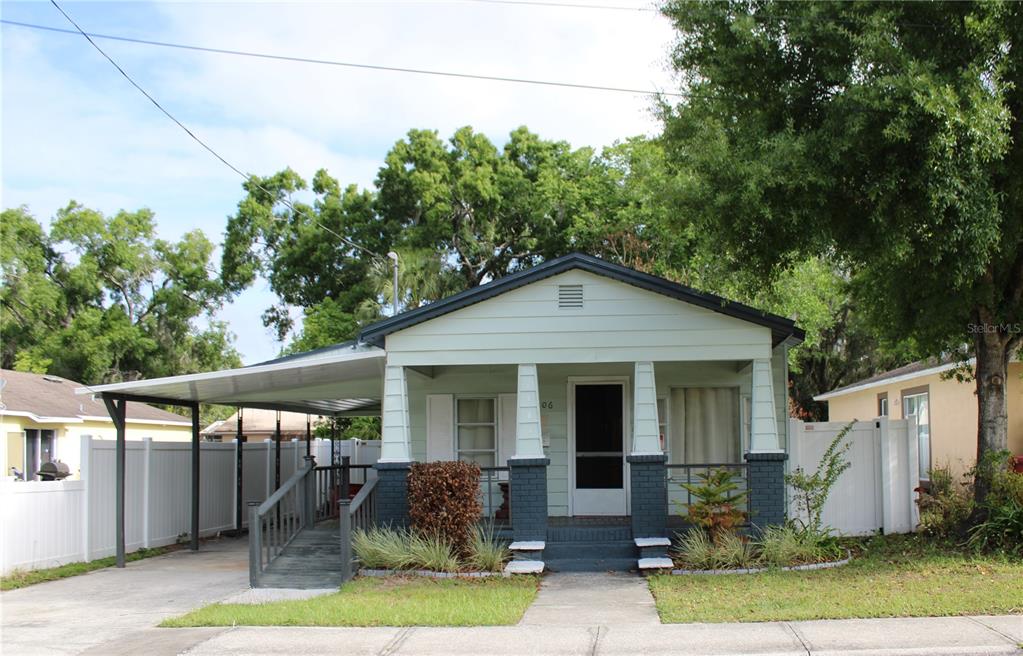 A light green bungalow with a front porch, metal carport, and a white privacy fence — 1106 E DR MARTIN LUTHER KING JR BOULEVARD, PLANT CITY, FL